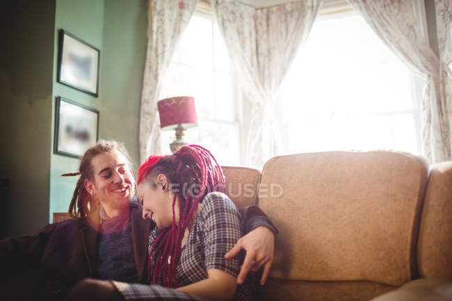 Улыбающаяся пара хипстеров сидит дома на диване — стоковое фото