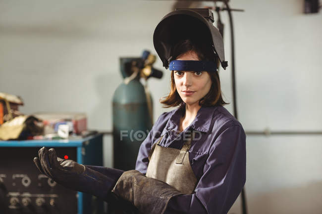 Retrato de soldador feminino usando luva na oficina — Fotografia de Stock