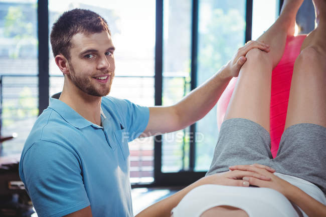 Чоловічий фізіотерапевт дає масаж ноги пацієнтці в клініці — стокове фото