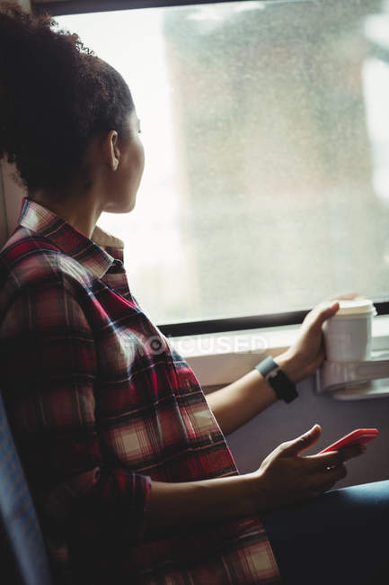 Продумана молода жінка дивиться крізь вікно, сидячи в поїзді — стокове фото