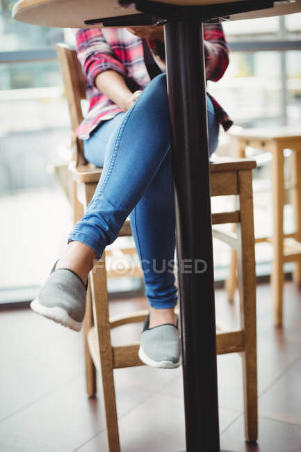 Baixa seção de mulher sentada à mesa no restaurante — Fotografia de Stock