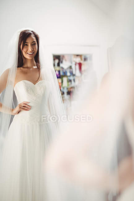 Sorrindo mulher tentando no vestido de noiva na loja — Fotografia de Stock