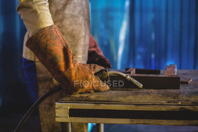 Imagen recortada del soldador masculino que sostiene la antorcha de soldadura en el taller - foto de stock