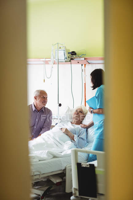 Seniorenpaar im Gespräch mit Krankenschwester im Krankenhaus — Stockfoto