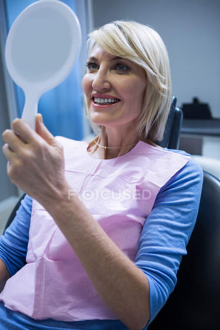 Patientin überprüft ihre Zähne im Spiegel in Zahnarztpraxis — Stockfoto