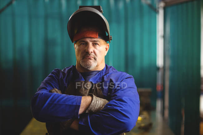 Portrait of handsome welder standing with arms crossed in workshop — Stock Photo