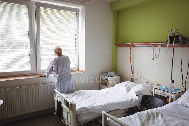 Старшая женщина стоит у окна в больнице — стоковое фото