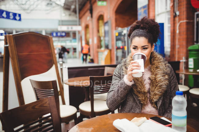 Frau trinkt Kaffee, während sie im Restaurant am Bahnhof sitzt — Stockfoto