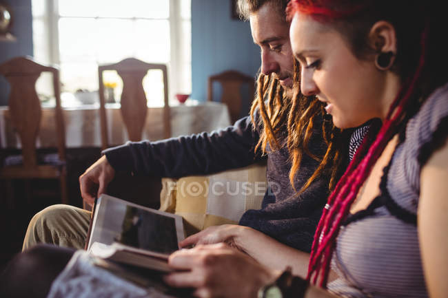 Casal jovem procurando álbum de fotos enquanto sentado em casa — Fotografia de Stock
