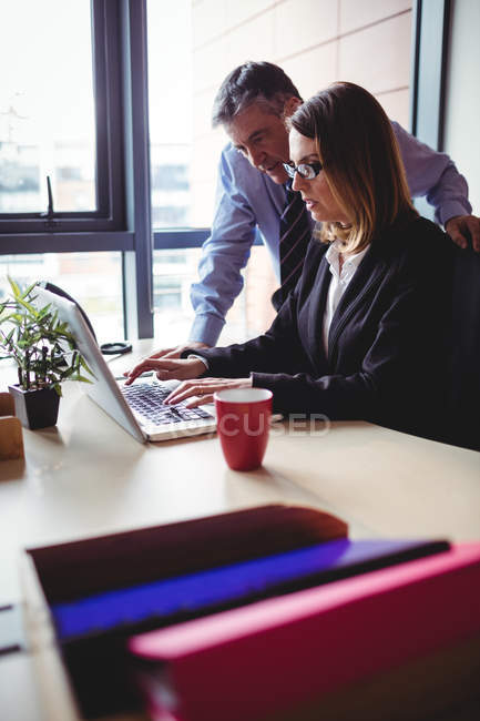 Businesspeople looking at laptop in office — Stock Photo