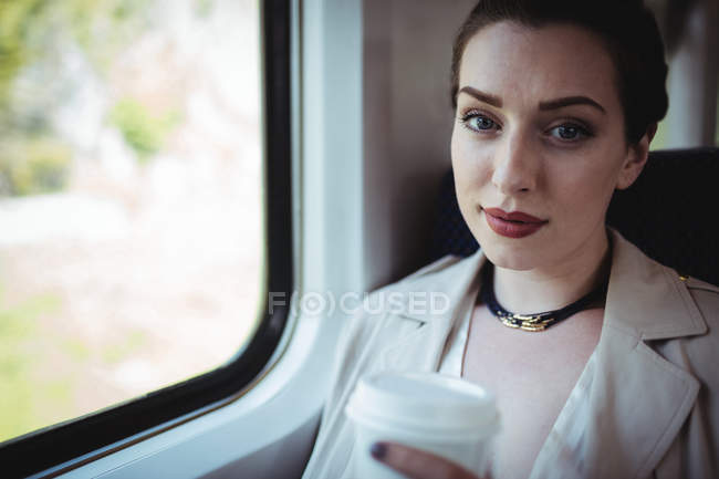 Portrait of beautiful woman sitting by window in train — Stock Photo