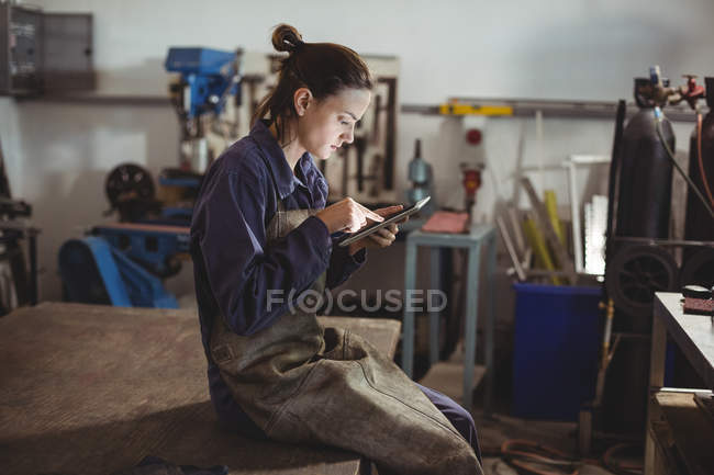 Female welder using digital tablet in workshop — Stock Photo