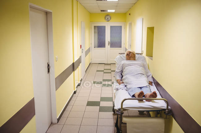 Senior woman lying on a stretcher in hospital corridor — Stock Photo