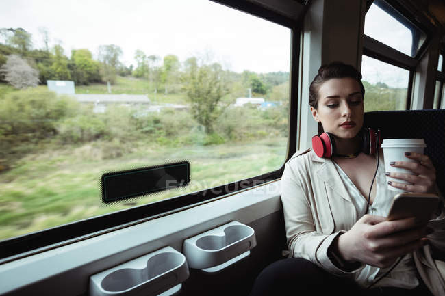 Молода жінка використовує мобільний телефон у потязі — стокове фото