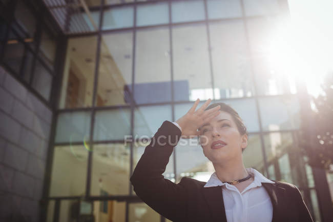 Junge Geschäftsfrau schirmt Augen gegen modernes Bauen ab — Stockfoto