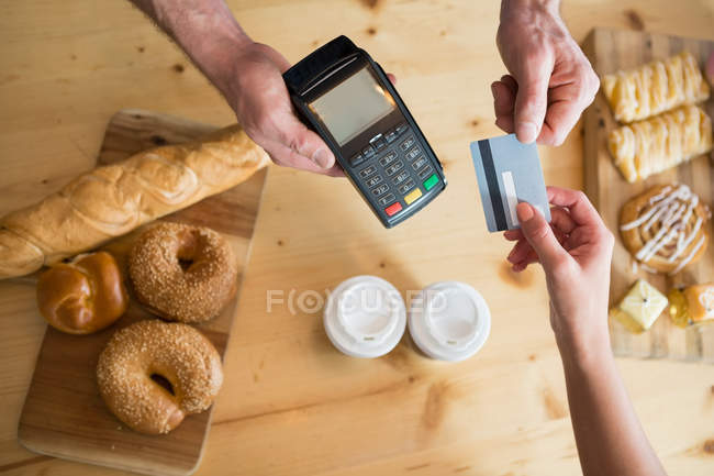 Cropped image of woman making payment with credit card in cafeteria — Stock Photo