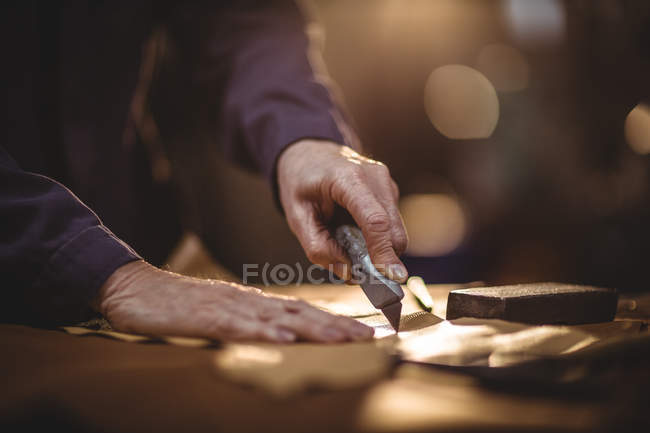 Mãos de sapateiro cortando um pedaço de couro na oficina — Fotografia de Stock