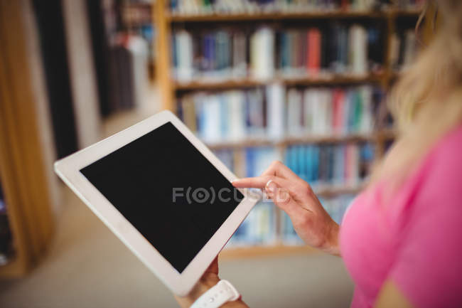 Обрезанное изображение женщины с помощью цифрового планшета в библиотеке — стоковое фото