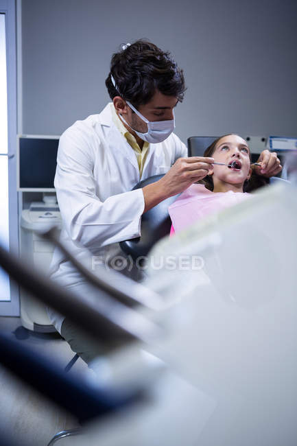 Zahnarzt untersucht junge Patientin in Zahnklinik mit Werkzeug — Stockfoto