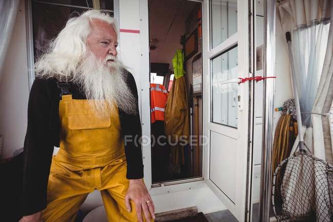 Pensativo pescador guapo sentado en el barco - foto de stock
