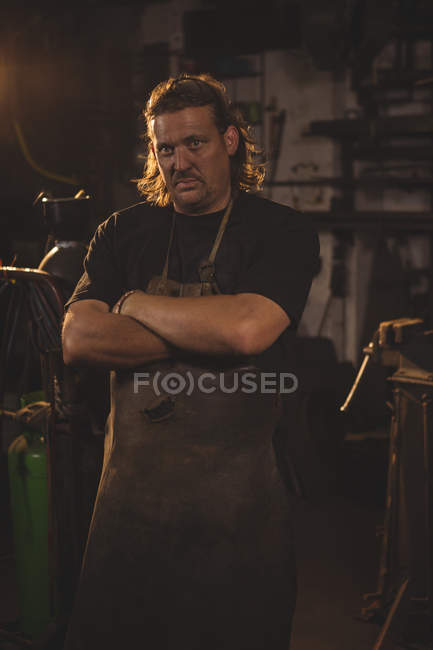 Portrait of blacksmith with arms crossed at work shop — Stock Photo