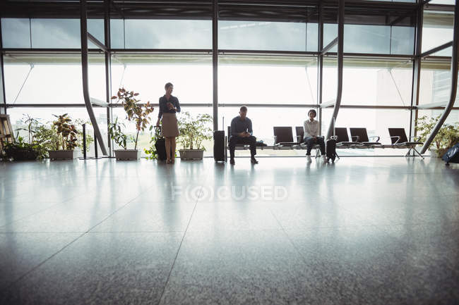 Ділові люди, що сидять з багажем у зоні очікування в терміналі аеропорту — стокове фото