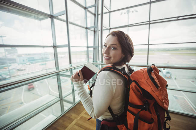 Retrato de mulher com passaporte em pé na área de espera no terminal do aeroporto — Fotografia de Stock