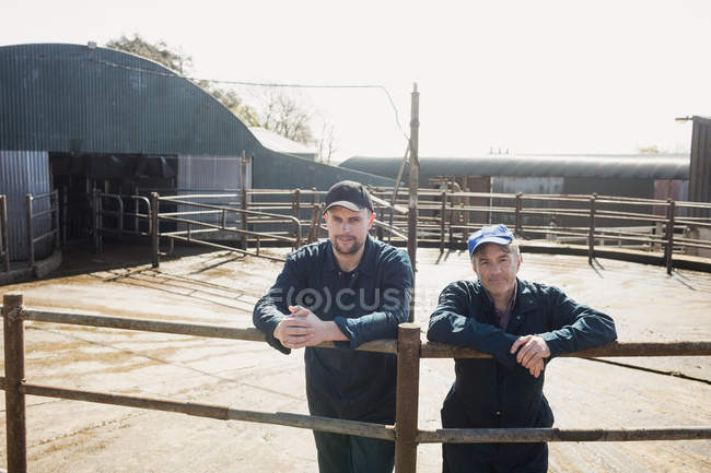 Retrato de compañeros de trabajo de pie junto a la valla en el granero - foto de stock