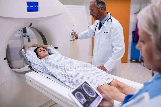 Médecin regardant l'IRM du cerveau scanner sur tablette numérique et patient entrant machine de balayage IRM à l'hôpital — Photo de stock