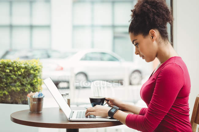 Вид збоку жінки, використовуючи ноутбук, сидячи в ресторані — стокове фото