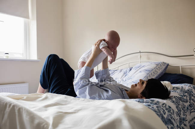 Mère jouant avec son fils dans la chambre à coucher à la maison — Photo de stock