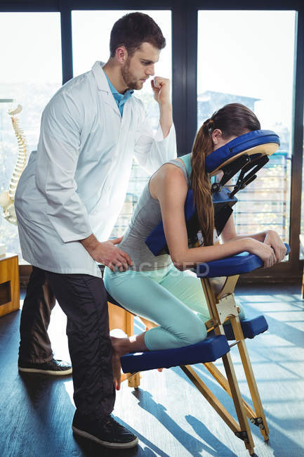 Физиотерапевт, дающий массаж спины пациентке в клинике — стоковое фото