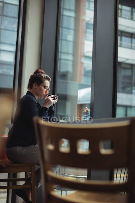 Jovem empresária cuidadosa bebendo café no café — Fotografia de Stock