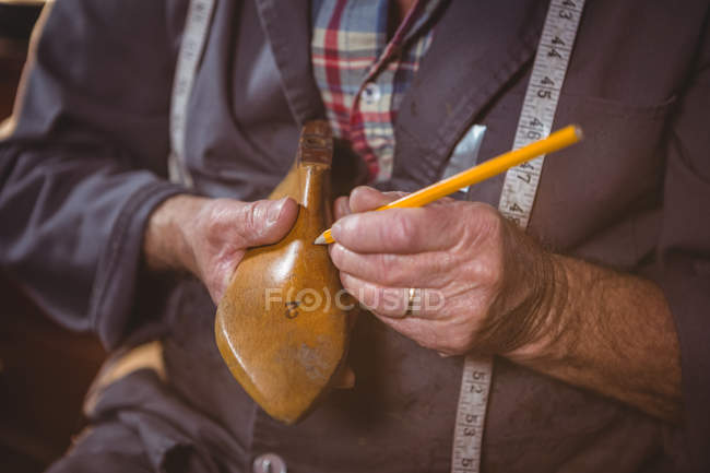 Primer plano de la marca del zapatero en el último zapato con pluma en el taller - foto de stock