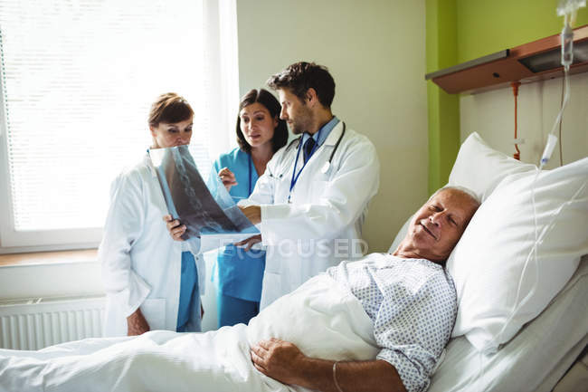 Médicos interagindo sobre o relatório de raios-X com paciente com paciente no hospital — Fotografia de Stock