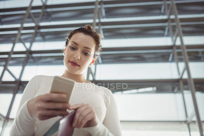 Jovem passageira usando telefone celular no terminal do aeroporto — Fotografia de Stock