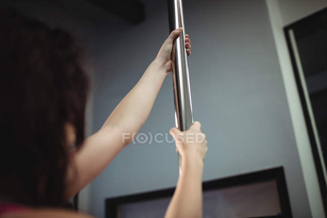 Imagen recortada de pole dancer holding pole en gimnasio - foto de stock