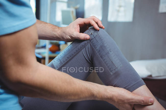 Cropped image of physiotherapist examining female patient knee with goniometer in clinic — Stock Photo
