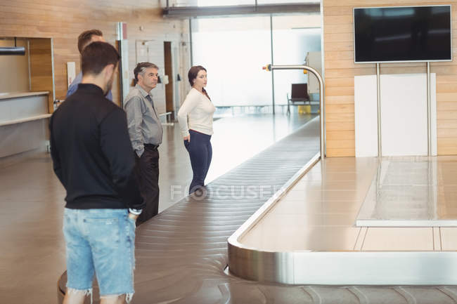 Pessoas esperando por bagagem na área de reclamação de bagagem no aeroporto — Fotografia de Stock