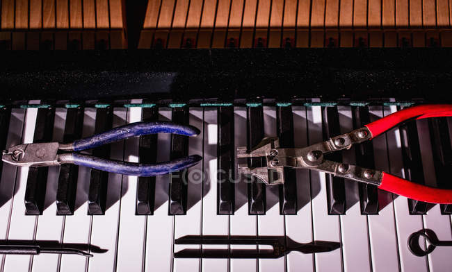 Primo piano degli strumenti di riparazione mantenuti sulla vecchia tastiera del pianoforte — Foto stock
