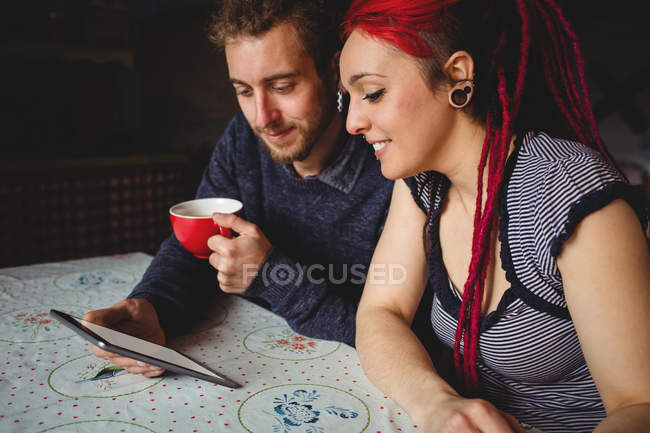 Feliz pareja hipster sosteniendo tableta digital en casa - foto de stock
