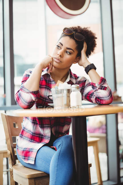 Jovem mulher pensativa sentada à mesa no restaurante — Fotografia de Stock