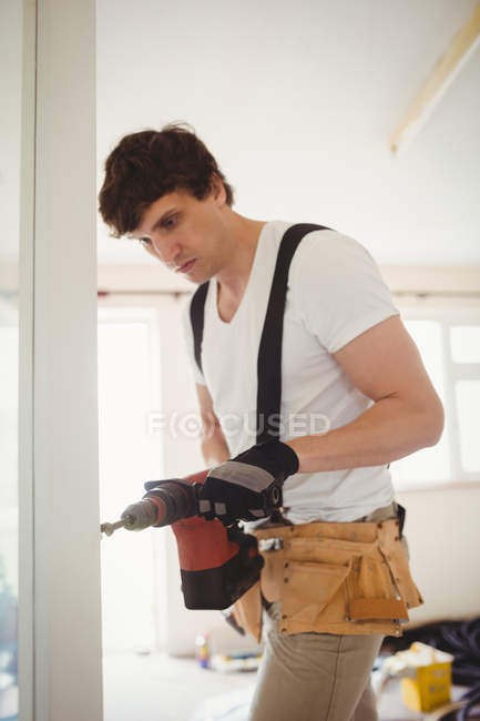 Carpenter drilling wooden door with drilling machine at home — Stock Photo
