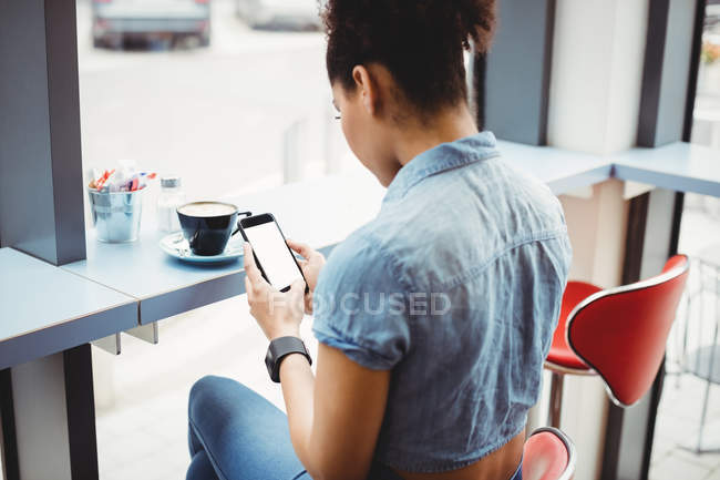 Жінка використовує мобільний телефон, сидячи в ресторані — стокове фото