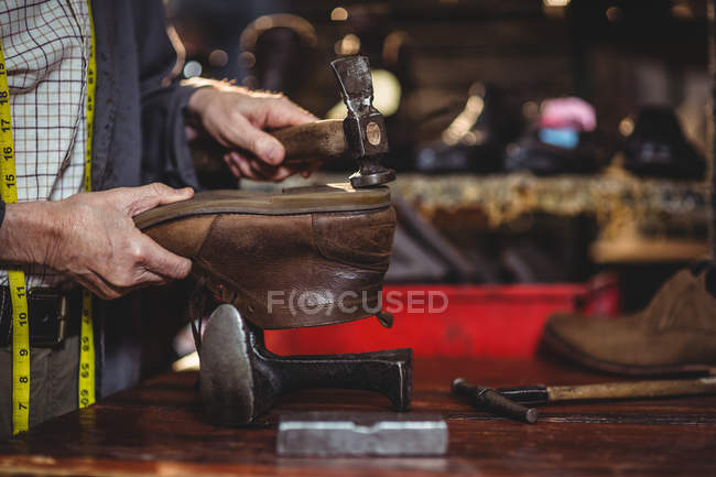 Hands of shoemaker hammering on a shoe in workshop — Stock Photo
