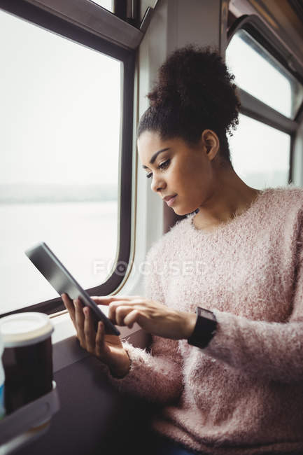 Mujer usando tableta digital mientras está sentado en el tren - foto de stock