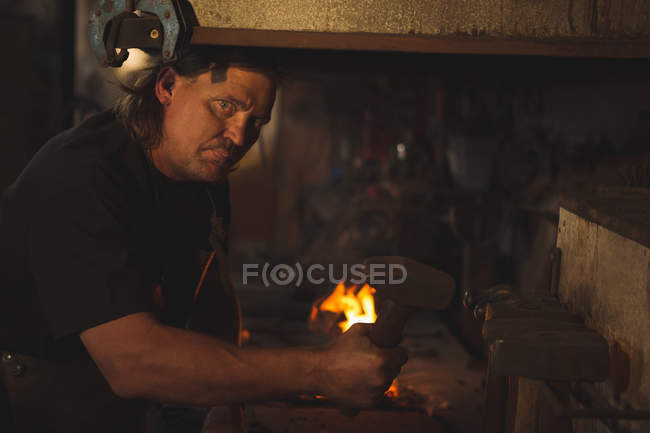 Portrait of blacksmith holding hammer at work shop — Stock Photo