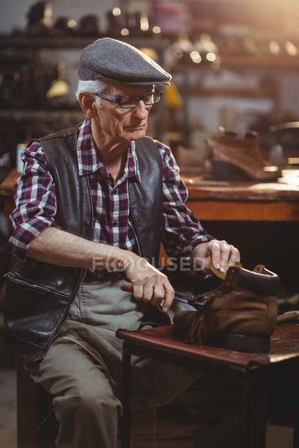 Обувщик чинит обувь в мастерской — стоковое фото
