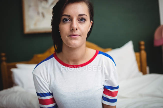 Retrato de una hermosa mujer sentada en la cama en el dormitorio - foto de stock
