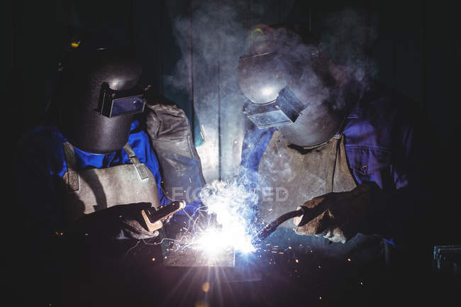 Deux soudeurs travaillant sur un morceau de métal en atelier — Photo de stock